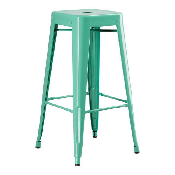 A Lancaster Table & Seating aquamarine metal backless barstool with a metal base.