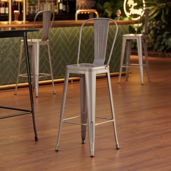 A Lancaster Table & Seating silver bar stool with metal legs at a bar table.