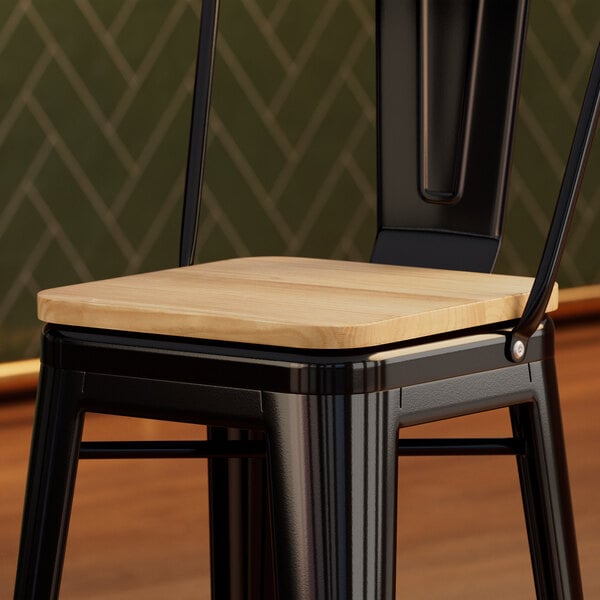 A Lancaster Table & Seating black metal chair with a natural wood seat.