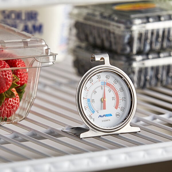 An AvaTemp dial refrigerator/freezer thermometer on a shelf.