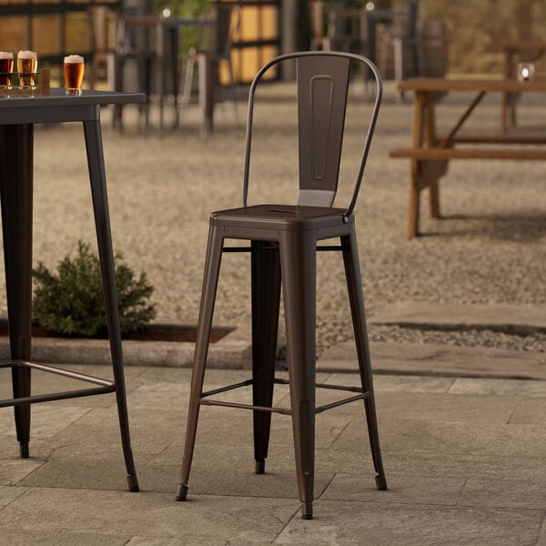 Three Lancaster Table & Seating Alloy Series Copper outdoor barstools on a patio.