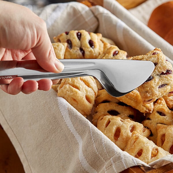 Polished stainless steel tongs holding a danish pastry