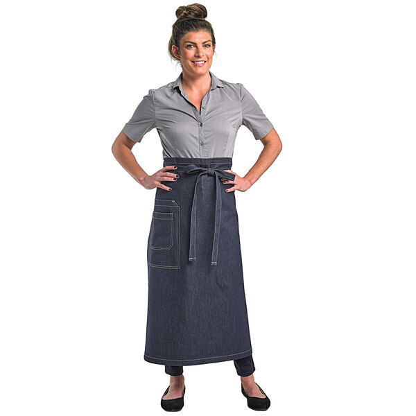 A woman wearing a Mercer Culinary denim bistro apron with two pockets.