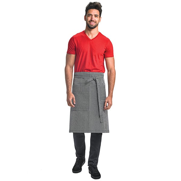 A man wearing a navy and white railroad stripe Mercer Culinary Bistro Apron with 3 pockets.
