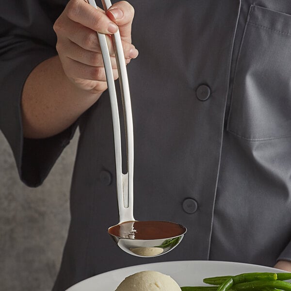 A person using a Vollrath stainless steel ladle to serve food.