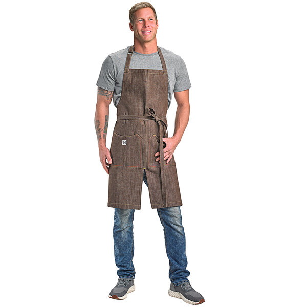A man wearing a Mercer Culinary brown denim bib apron.