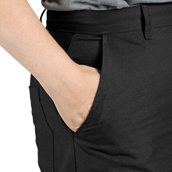 A person wearing Uncommon Chef black straight leg pants with their hand in their pocket.