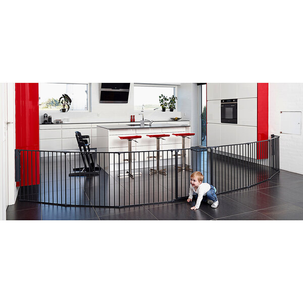 A baby crawling on a black BabyDan room divider gate.