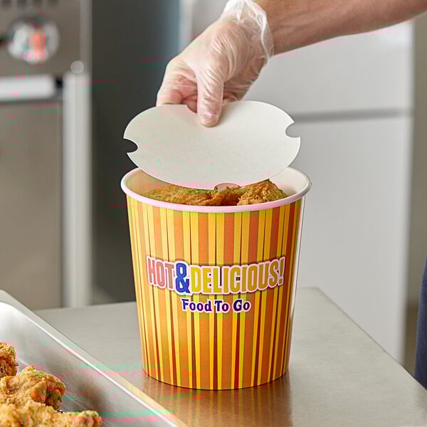 A hand putting a paper lid on a Choice hot food bucket.