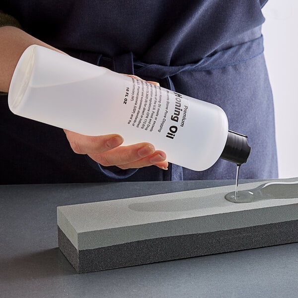 A person pouring Tablecraft Premium Honing Oil onto a stone.