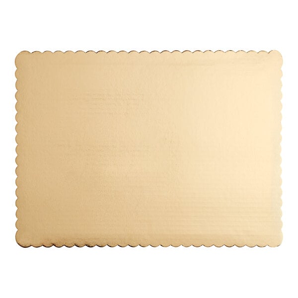 A close up of a gold laminated rectangular paper cake pad with scalloped edges.