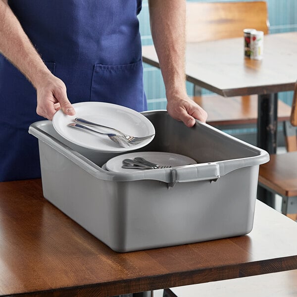 A gray high density polyethylene bus tub being used to collect dirty dishes and utensils.
