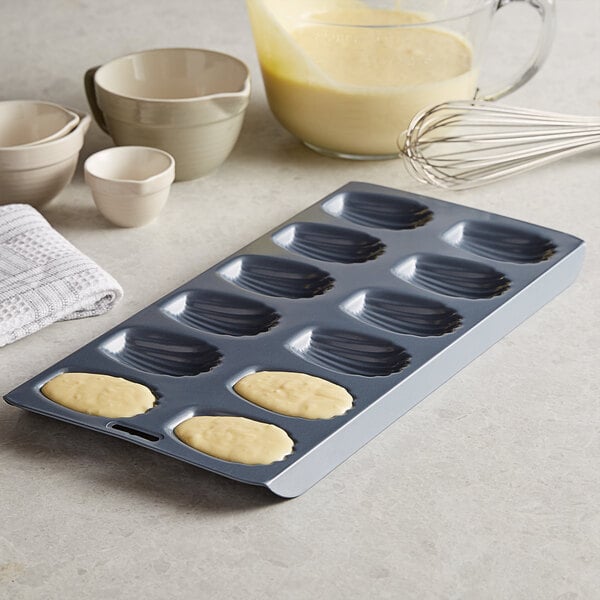 A Fox Run Madeleine sheet pan with 12 madeleines in it.