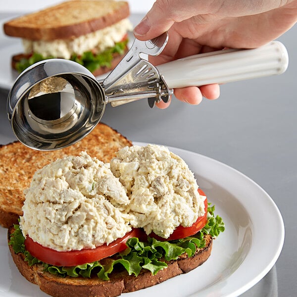 A hand holds a Hamilton Beach ivory metal scoop over a sandwich.