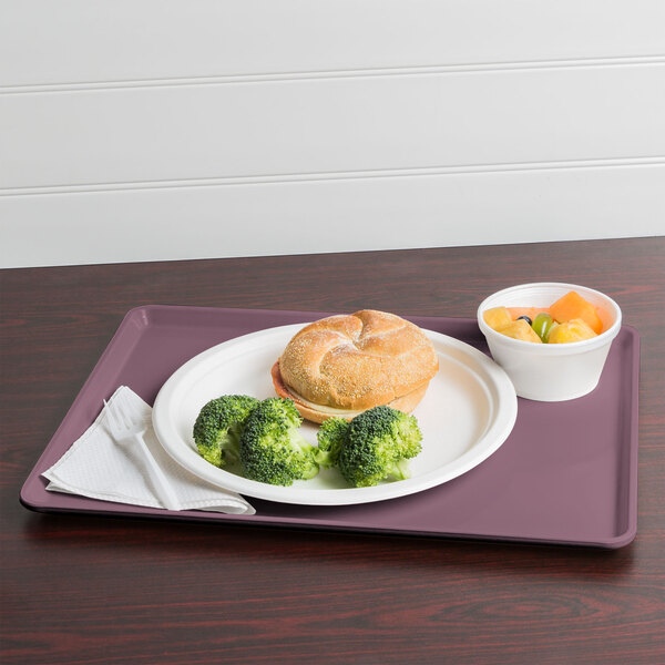 A Cambro grape dietary tray with food, including a sandwich, broccoli, and fruit.