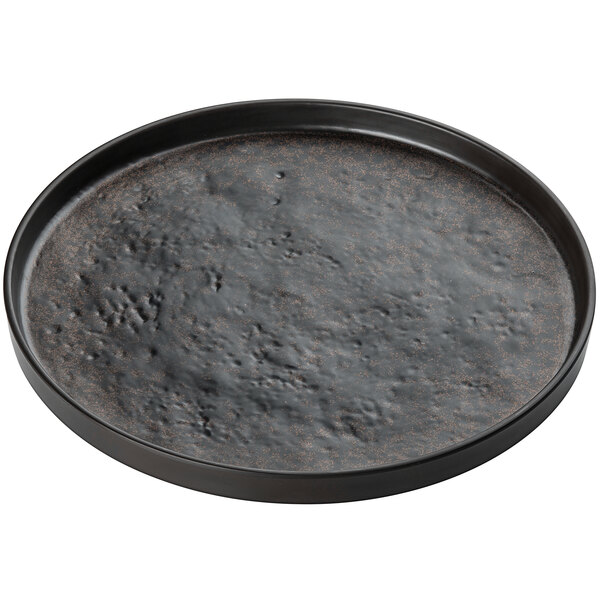 a black round pan with a brown speckled surface