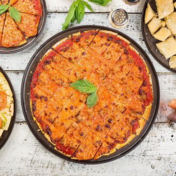 A Tablecraft Lunara brown melamine platter holding a variety of pizzas on a table.
