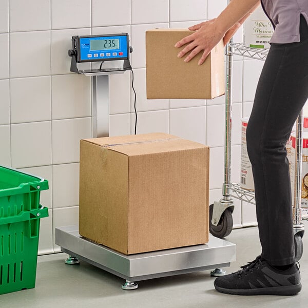 A person weighing a brown box on an AvaWeigh digital receiving scale with a tower display.