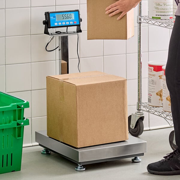 A person weighing a brown box on an AvaWeigh digital receiving bench scale.