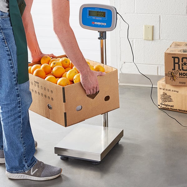 Hombre inclinándose para pesar una caja de naranjas en una báscula receptora