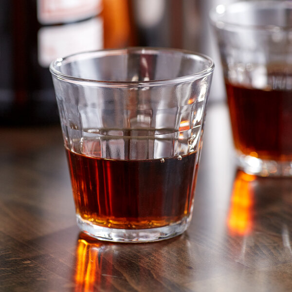A glass of brown liquid sits on a table.