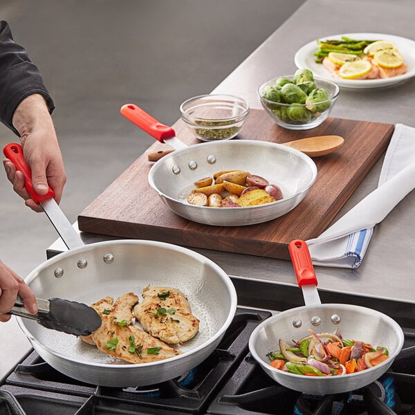 A person cooking potatoes and onions in a Choice aluminum frying pan with vegetables.