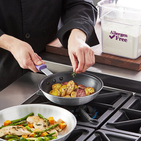 A person cooking food in a Choice purple-handled fry pan.