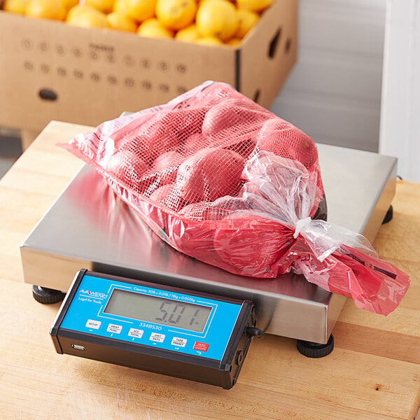 An AvaWeigh digital receiving scale on a counter with a bag of yellow fruit on it.