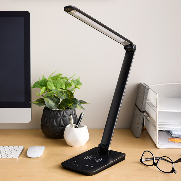 A black LED desk lamp with a multi-pivot adjustable arm, wireless charging base, and USB port.