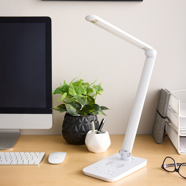 A white LED desk lamp with a multi-pivot adjustable arm, wireless charging base, and USB port.