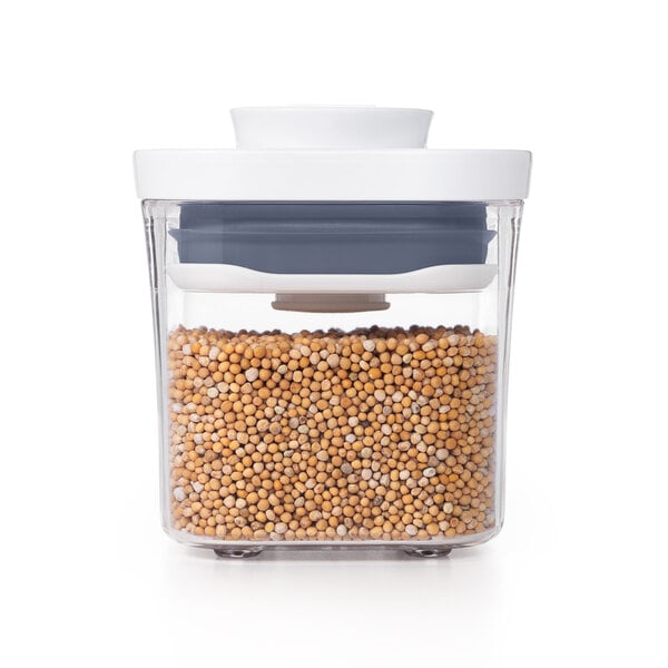 An OXO food storage container with a white lid filled with yellow and white beans.