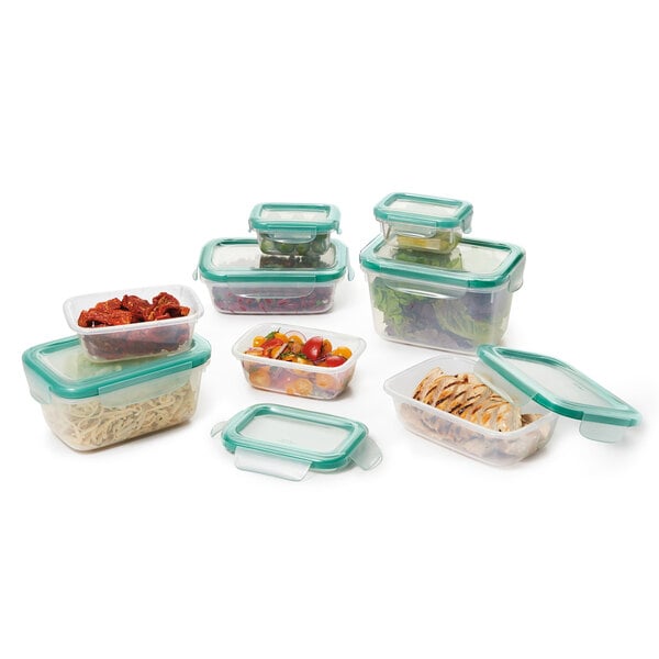 A stack of OXO Good Grips rectangular plastic containers with green snap-on lids filled with food.