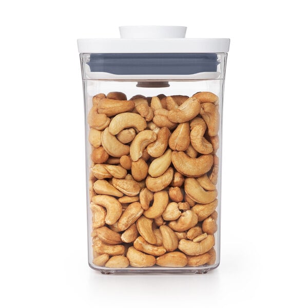 A clear plastic OXO food storage container full of cashews.
