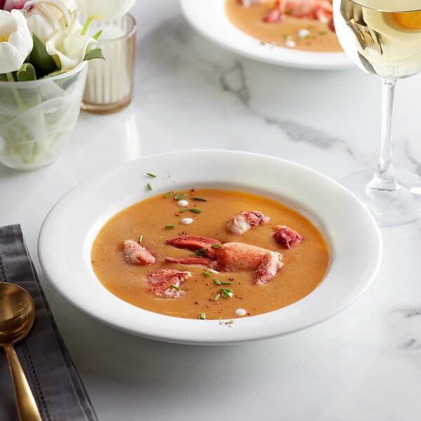 a bowl of soup with lobster and a glass of wine