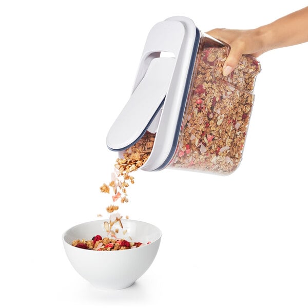 A hand pouring cereal from an OXO Good Grips container into a bowl.