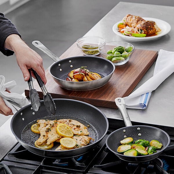 A person cooking brussels sprouts in a Vollrath Optio frying pan.