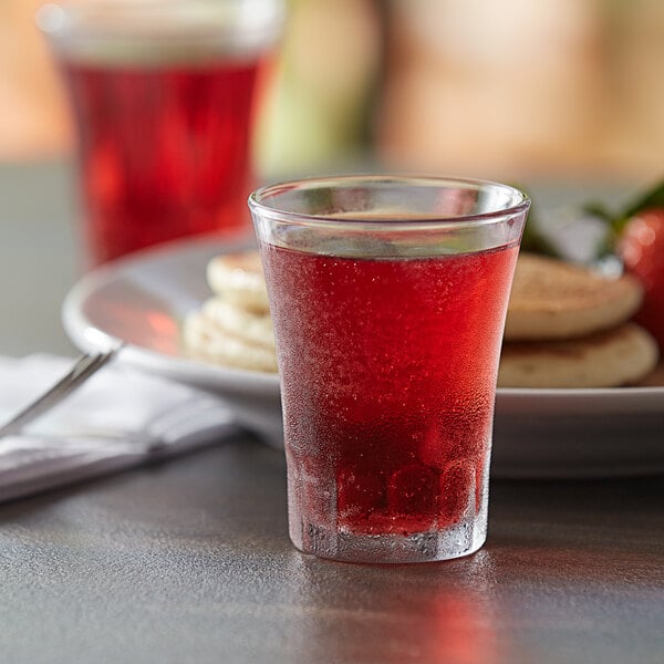A Duralex Amalfi glass filled with red liquid on a table.