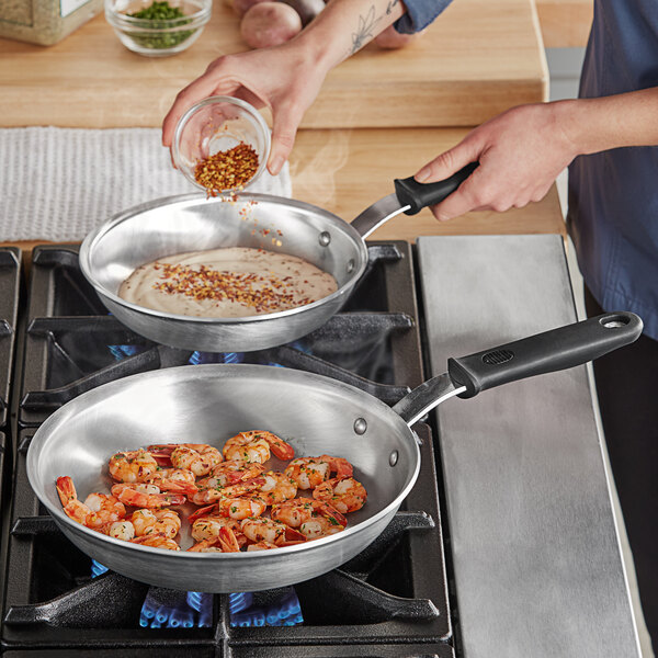 A person seasoning shrimp in a Vollrath Wear-Ever frying pan.