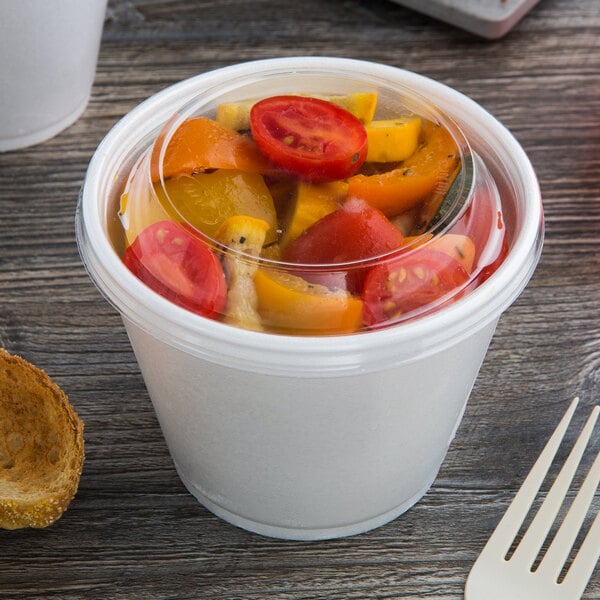 A clear Dart dome lid on a container of food on a table.