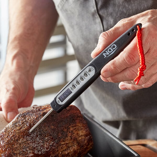 A man using a CDN digital pocket probe thermometer to check the temperature of a steak.