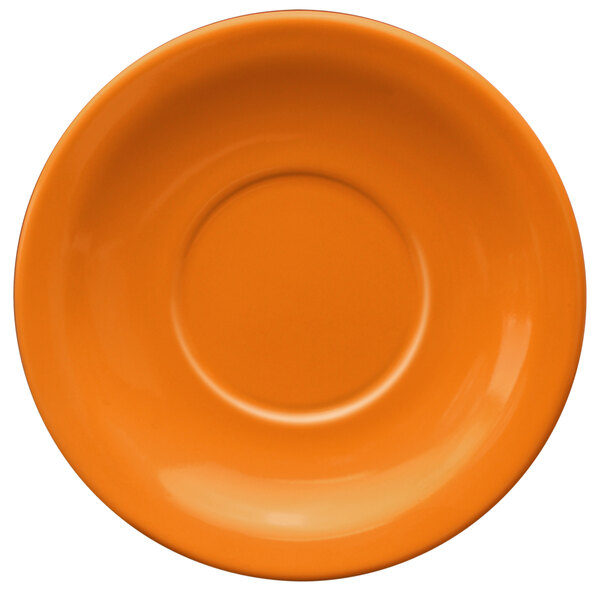 An orange stoneware saucer with a circle in the middle.