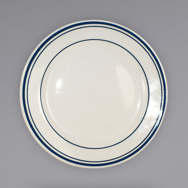 An ivory stoneware plate with blue lines on the rim.