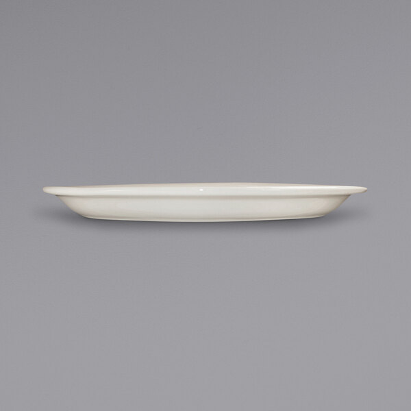 A white International Tableware Valencia narrow rim stoneware platter on a gray surface.