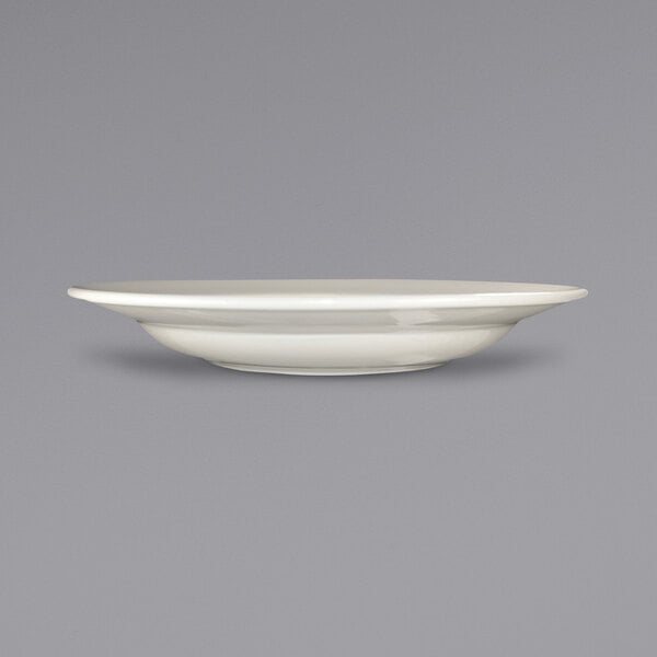 A close up of an International Tableware Roma ivory stoneware bowl with a rolled edge on a white background.