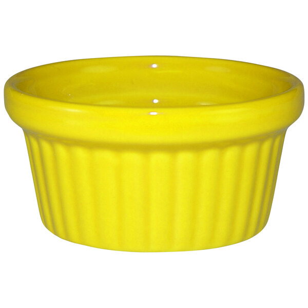 A yellow stoneware fluted ramekin with a ruffled edge.
