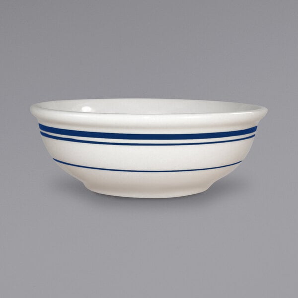 A close up of a white International Tableware stoneware bowl with blue lines.