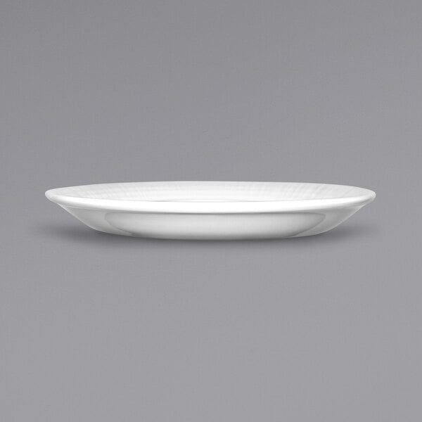 A white porcelain saucer with a rim on a gray background.