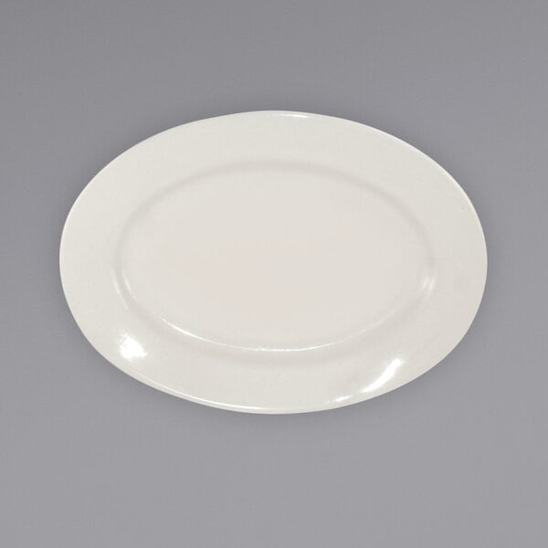 An International Tableware ivory stoneware platter with a wide rim on a gray surface.