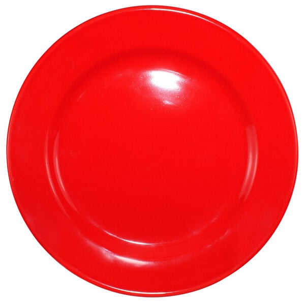 A red International Tableware stoneware plate with a rolled edge and wide rim.