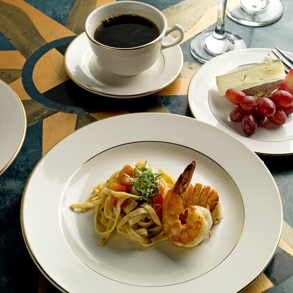 An International Tableware Florentine stoneware plate with shrimp, grapes and wine on a table.